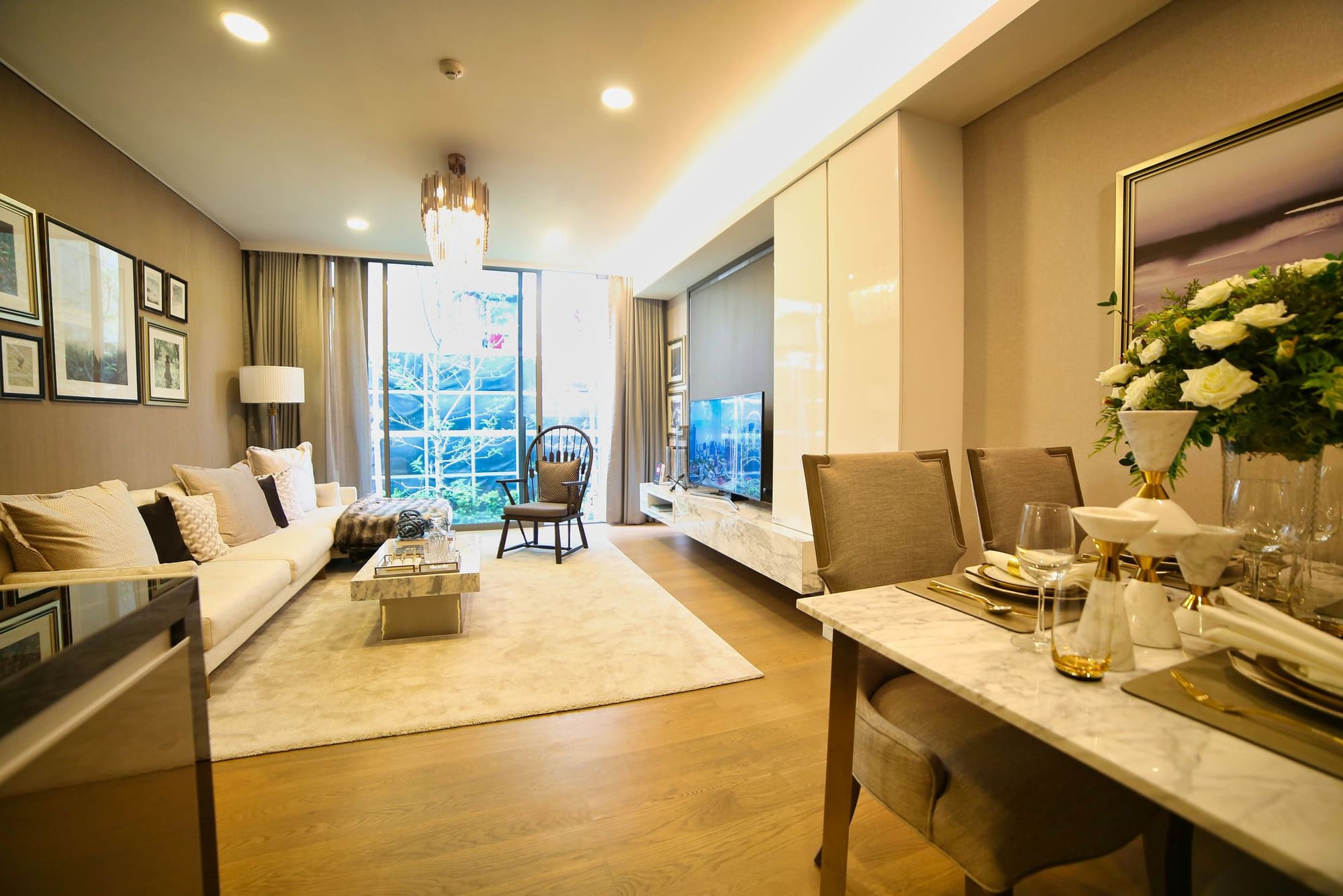 Luxury apartment living room with marble dining table, cream sofa, and city skyline views through floor-to-ceiling windows