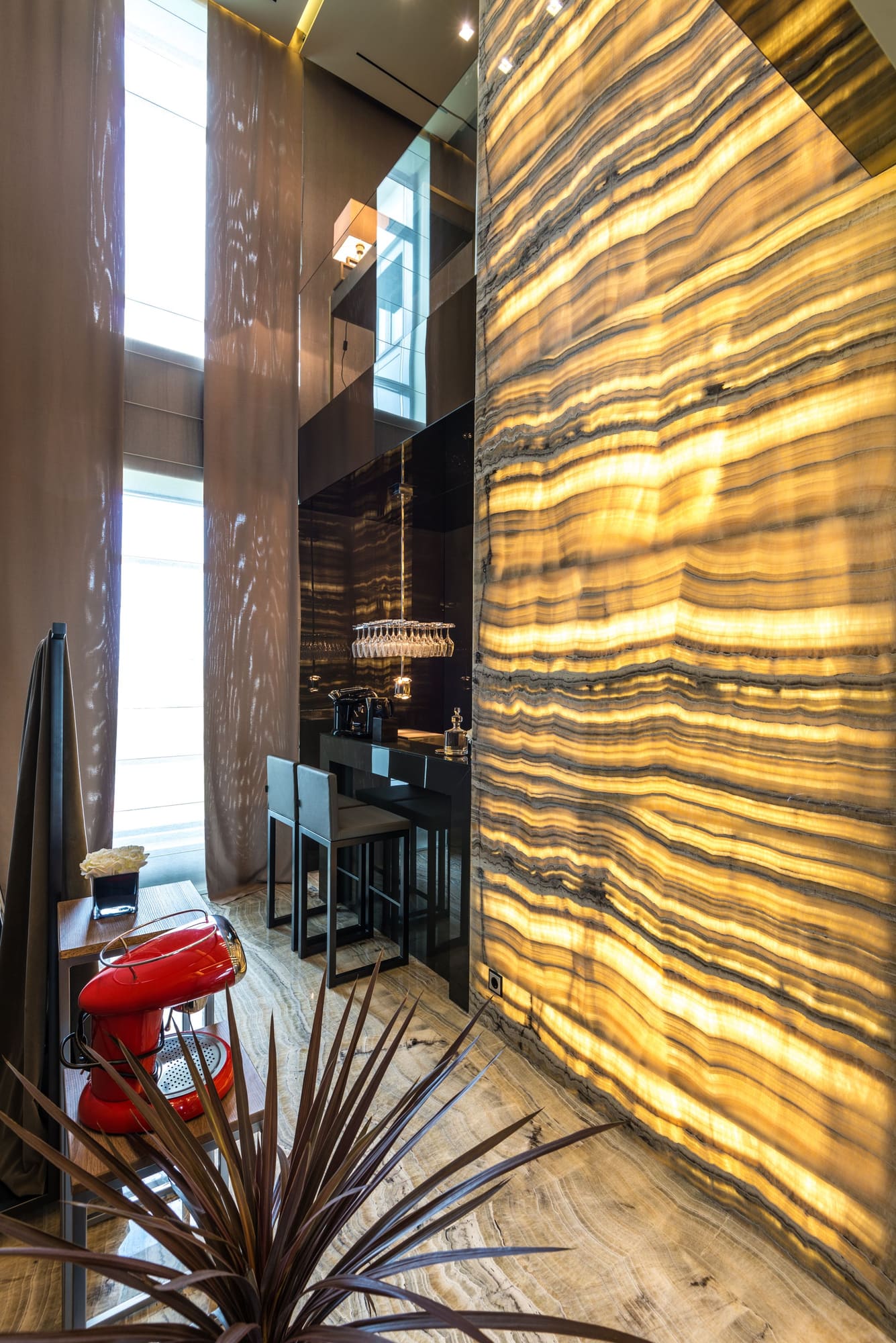Luxury bathroom with backlit golden onyx wall panels, black vanity with mirror, and modern fixtures