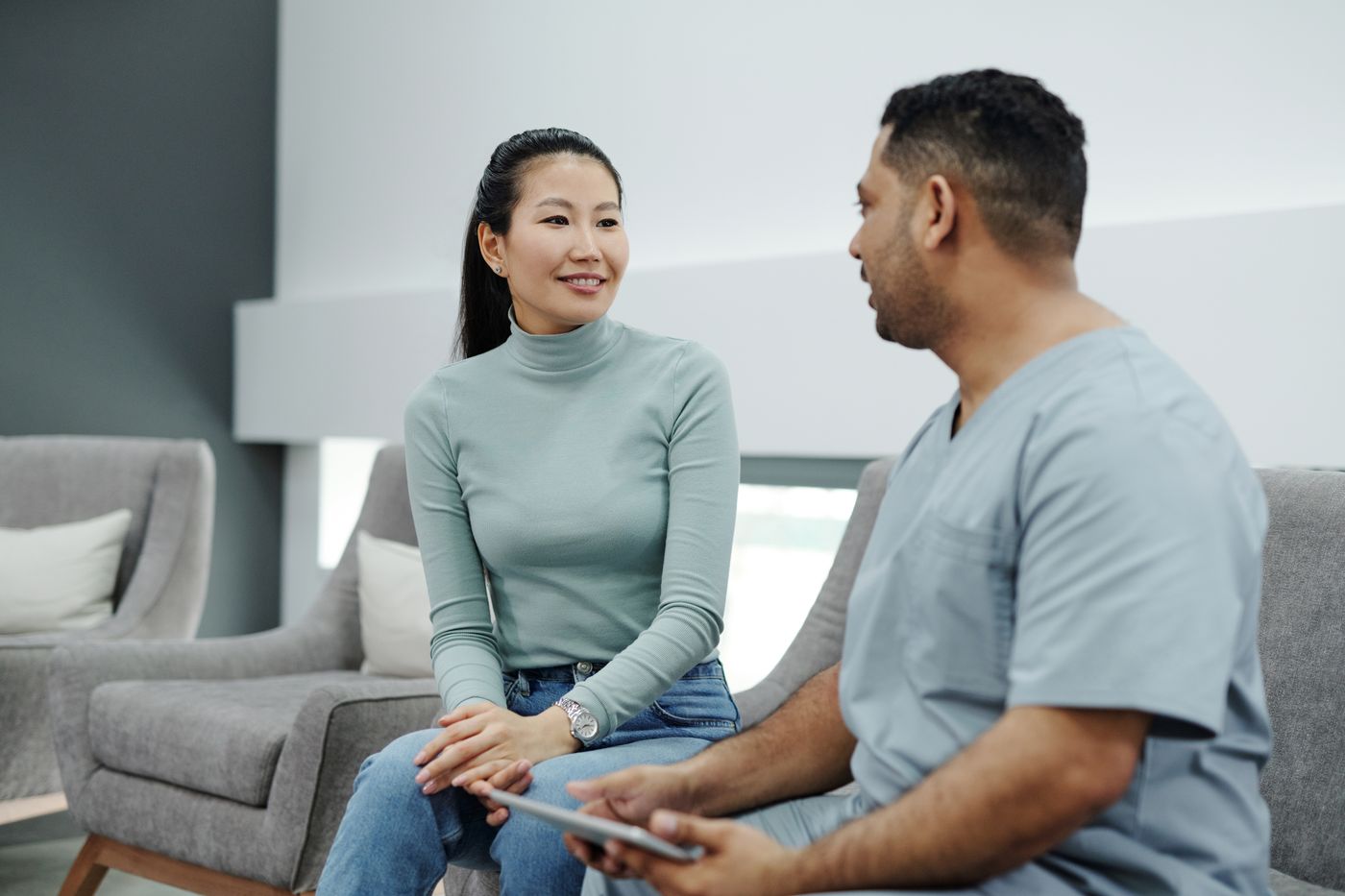 Two people sitting on a gray couch having a conversation in a modern living room